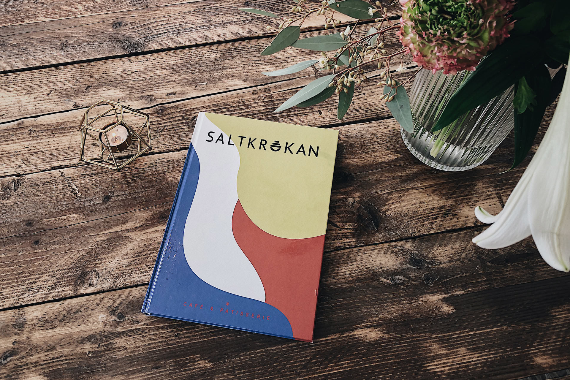 Saltkrokan Menü mit Logo und farbiger Markenillustration auf einem Holztisch